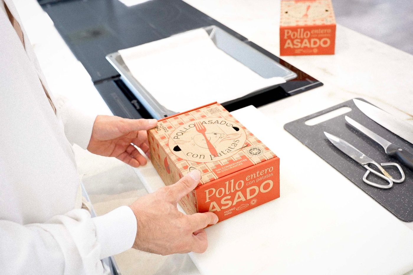 Un cocinero abre la caja kraft del pollo asado entero con patatas de Mórrofino