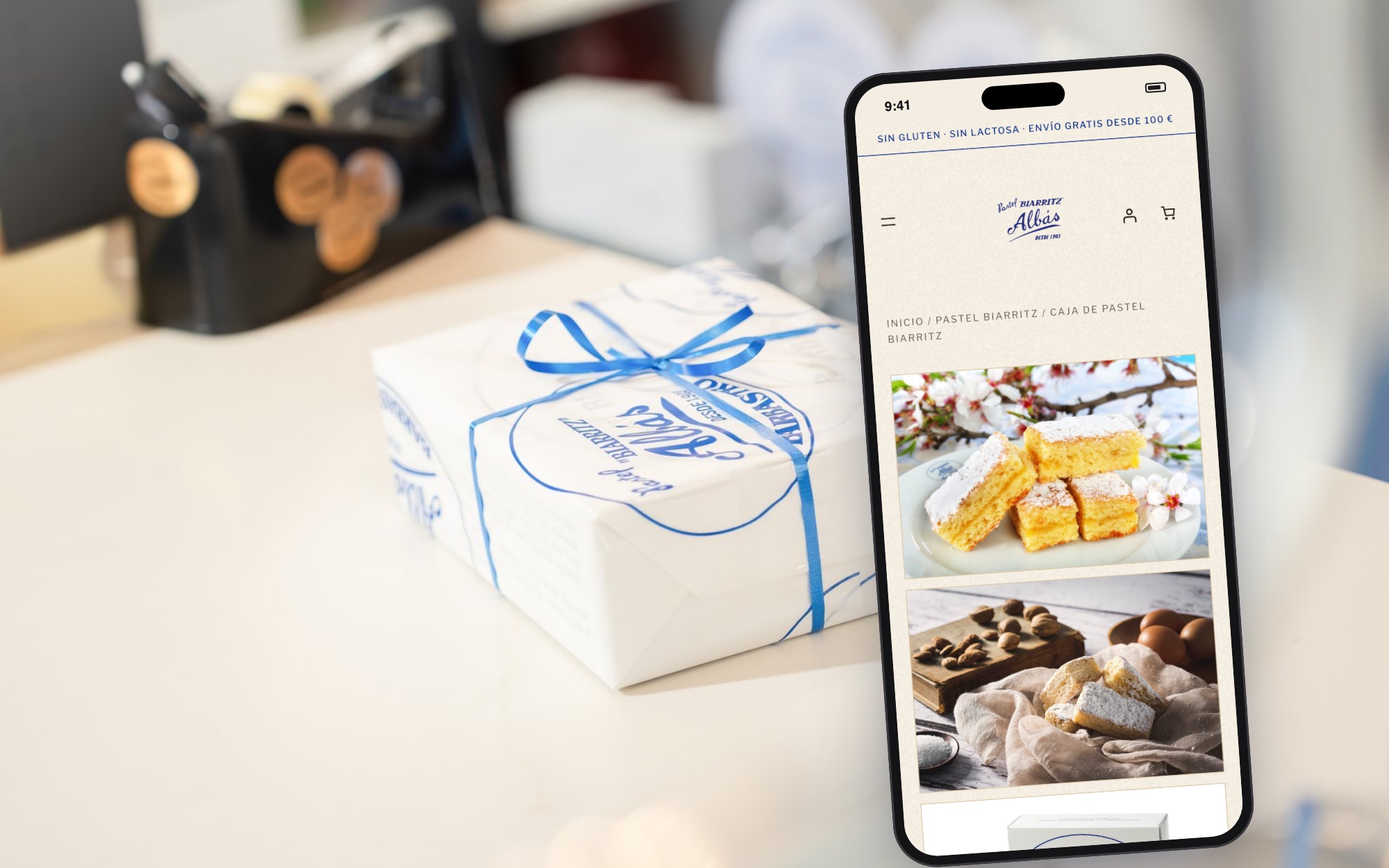 Caja de Pastel Biarritz con lazo azul junto a un móvil con su ficha en la tienda online